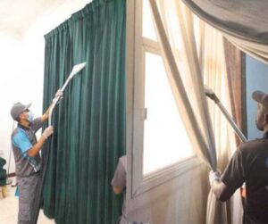 Professional cleaners vacuuming and deep cleaning curtains in a home